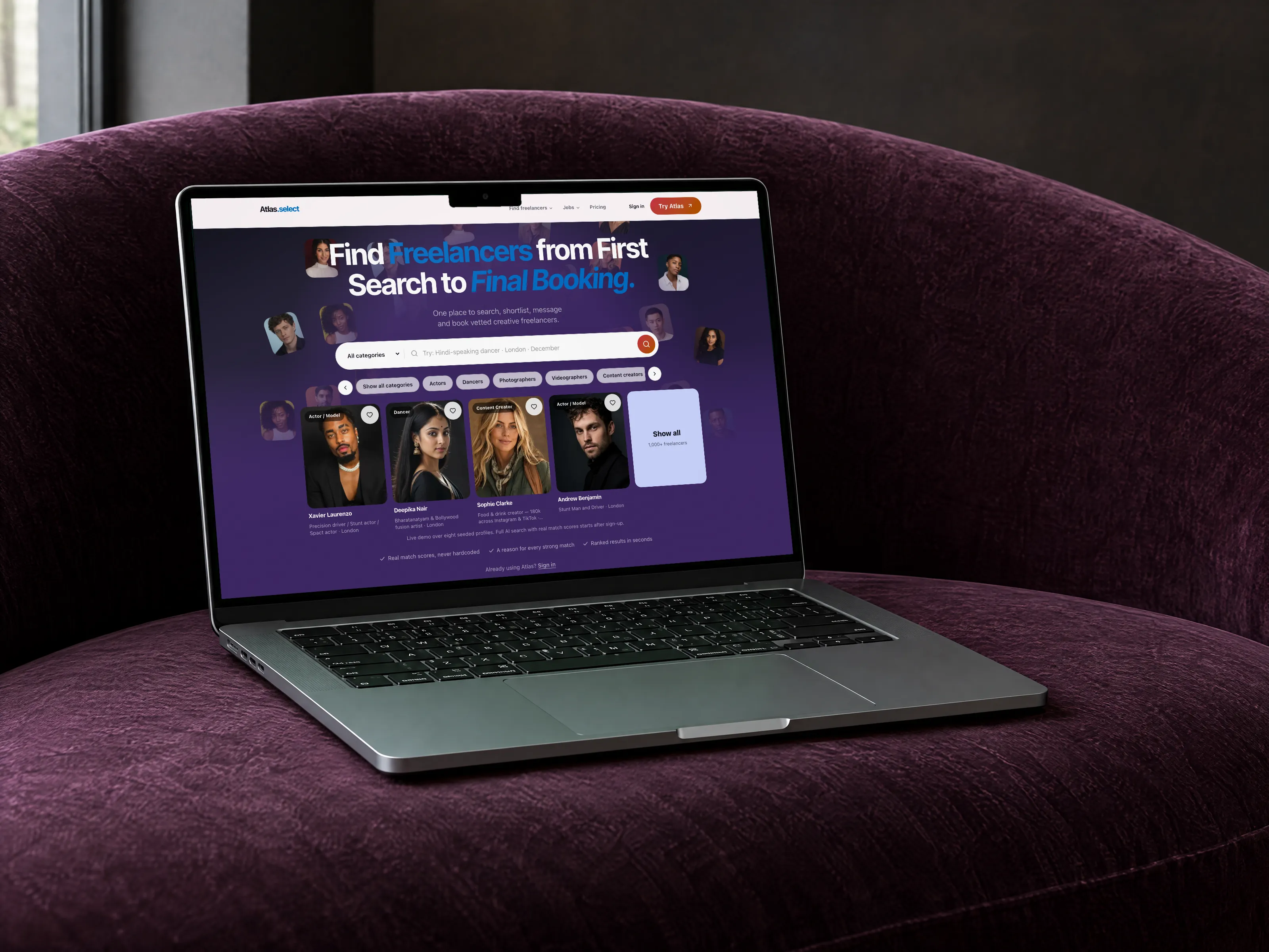 Atlas freelancer booking web app on a MacBook Pro on a plum velvet sofa