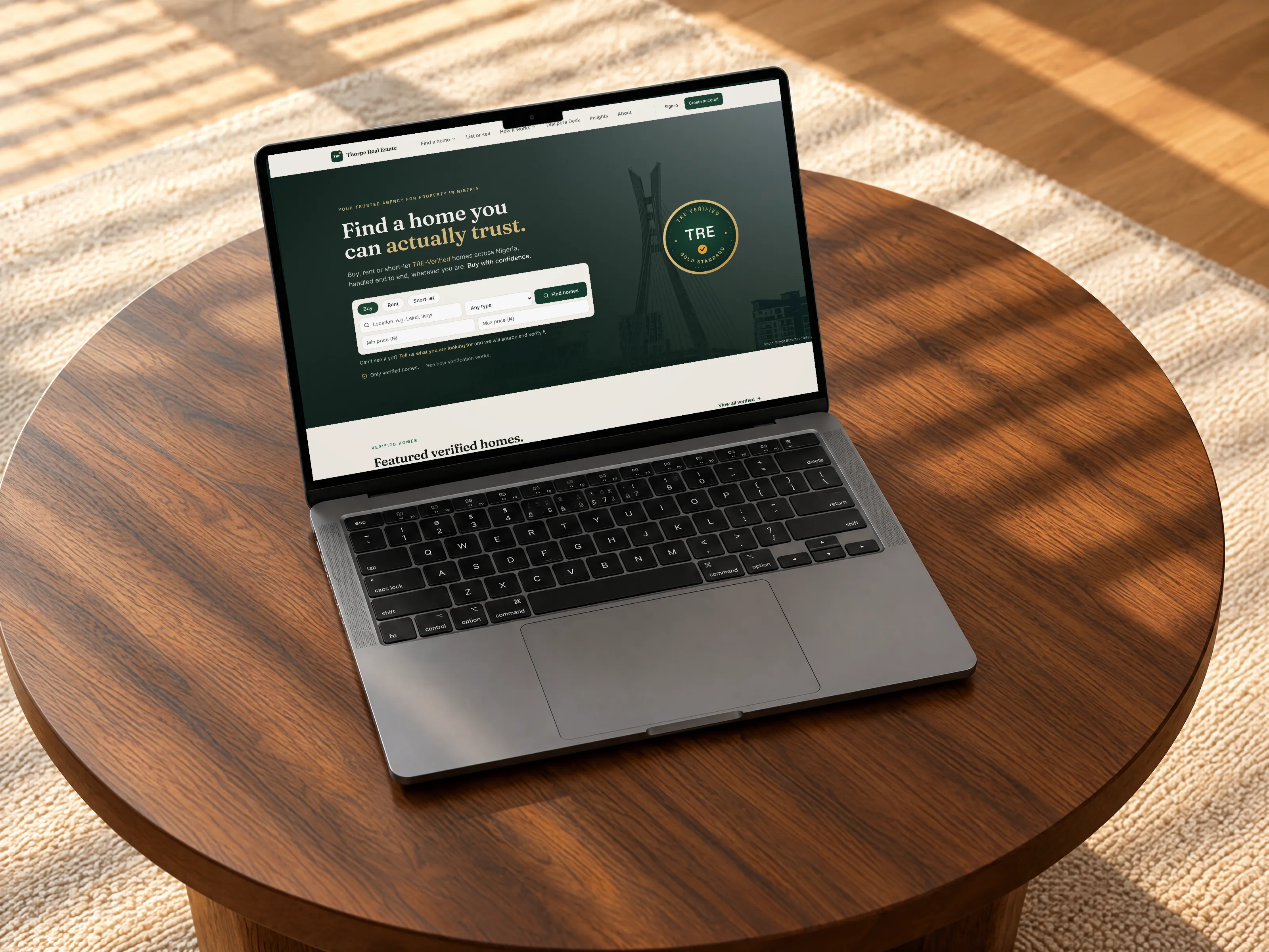 Thorpe Real Estate website on a MacBook Pro on a walnut coffee table in a sunlit living room